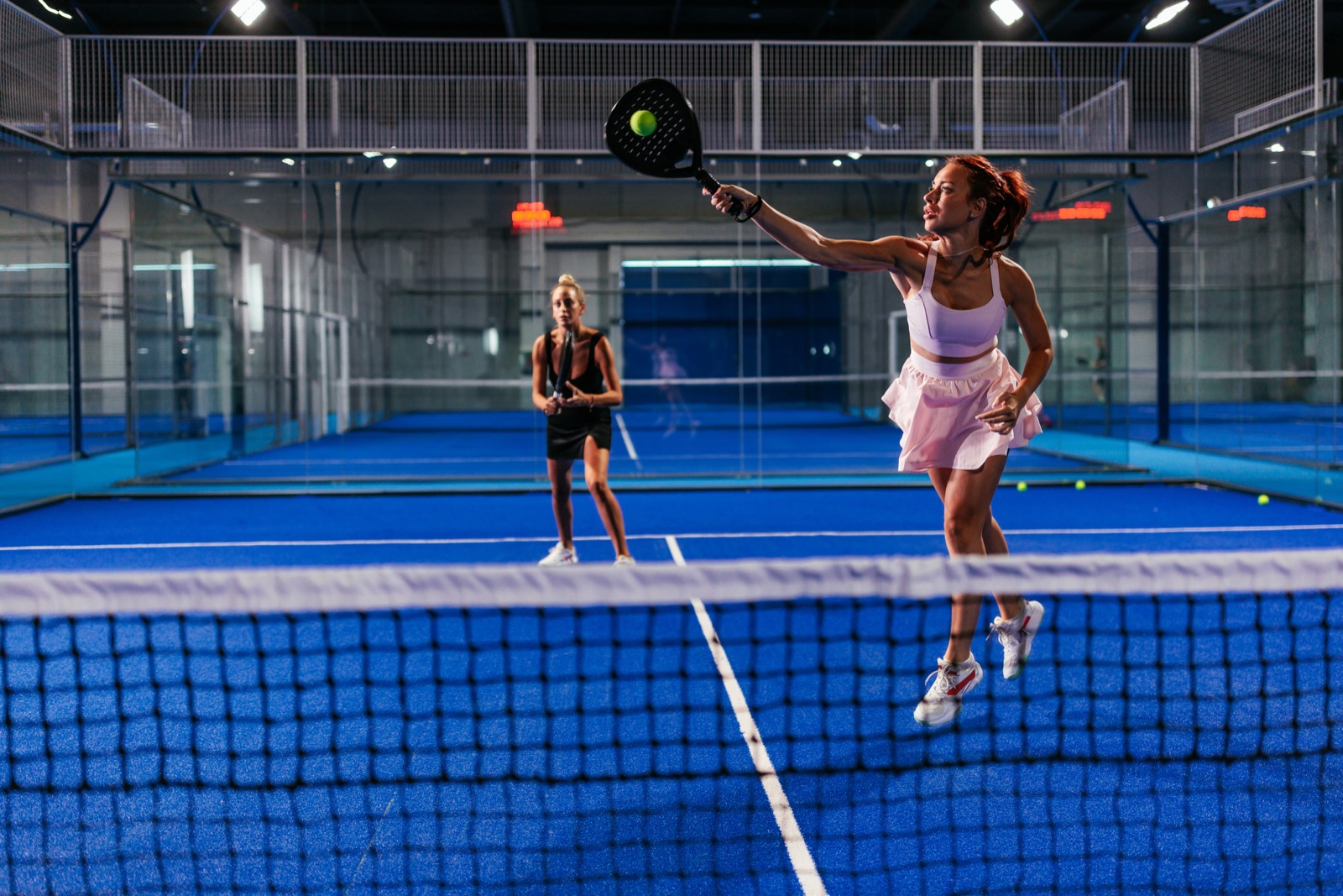 Pilates for Racket Sports — two players mid-rally on an indoor padel court